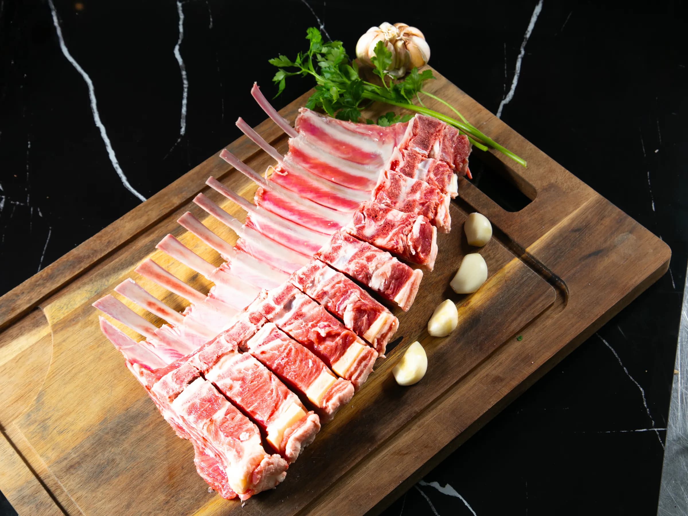 Rack de cordero estilo francés dispuesto sobre una tabla